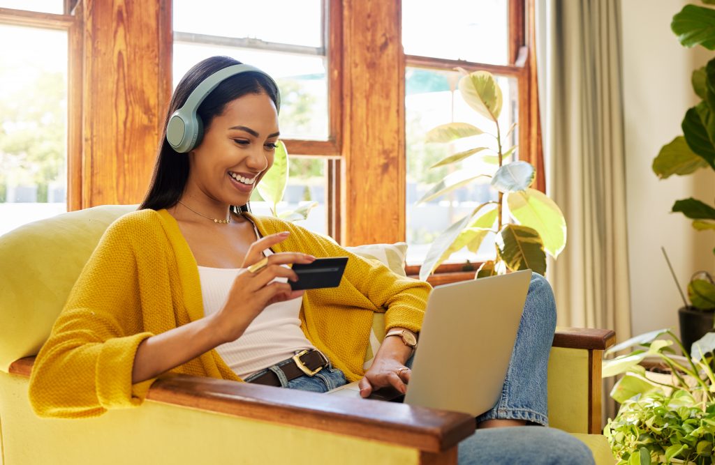 A woman on laptop shopping with credit card in hand.